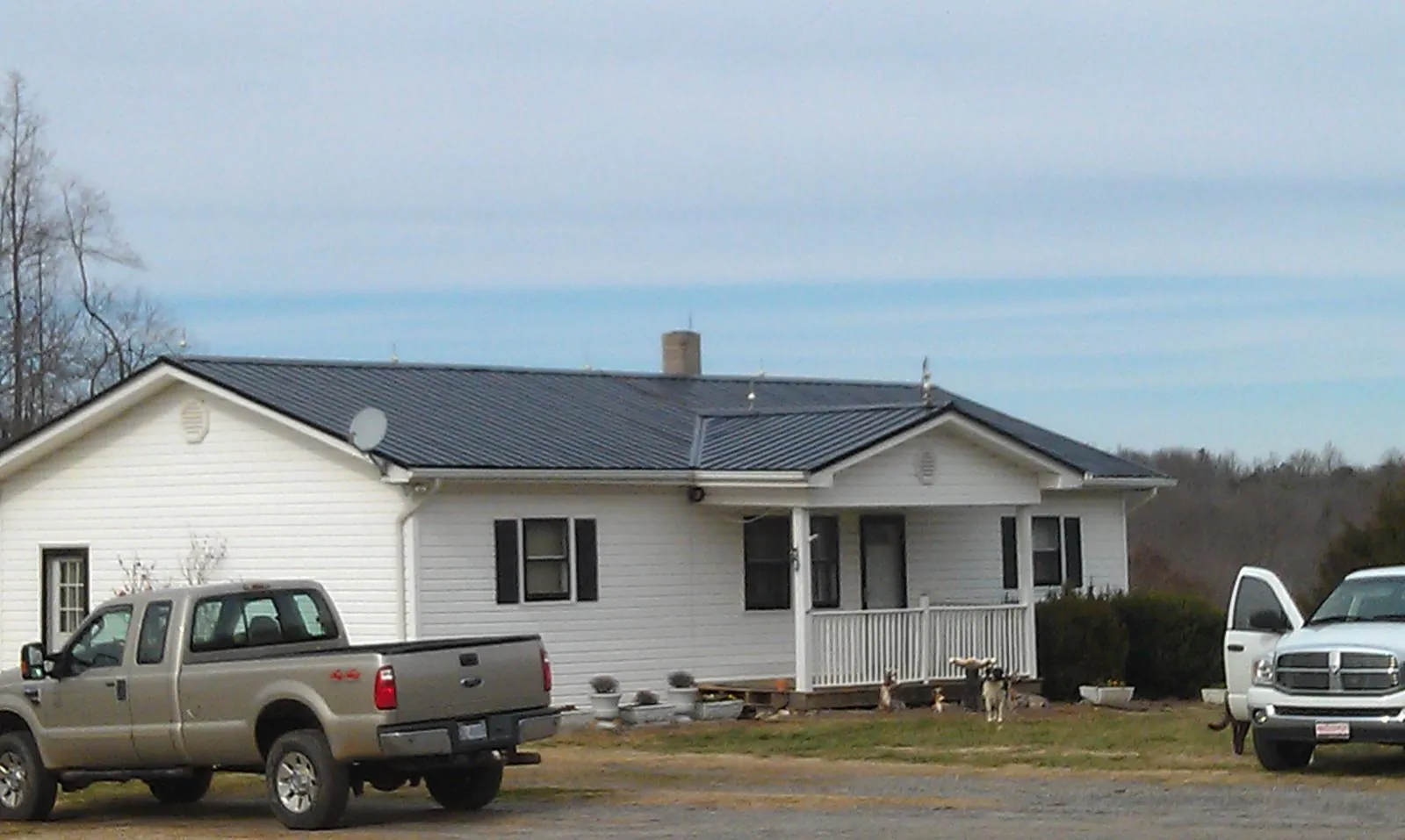 Finished dark metal roof on a white ranch home with work trucks parked in Somerville
